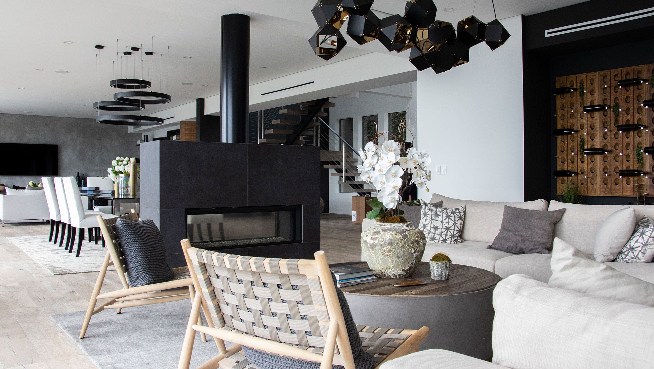 The interior space of the event venue. The space has an overall cool color palette with black, gray, and cream and the furniture, lighting fixtures, and fireplace are large and stylish. The space is filled with natural light.