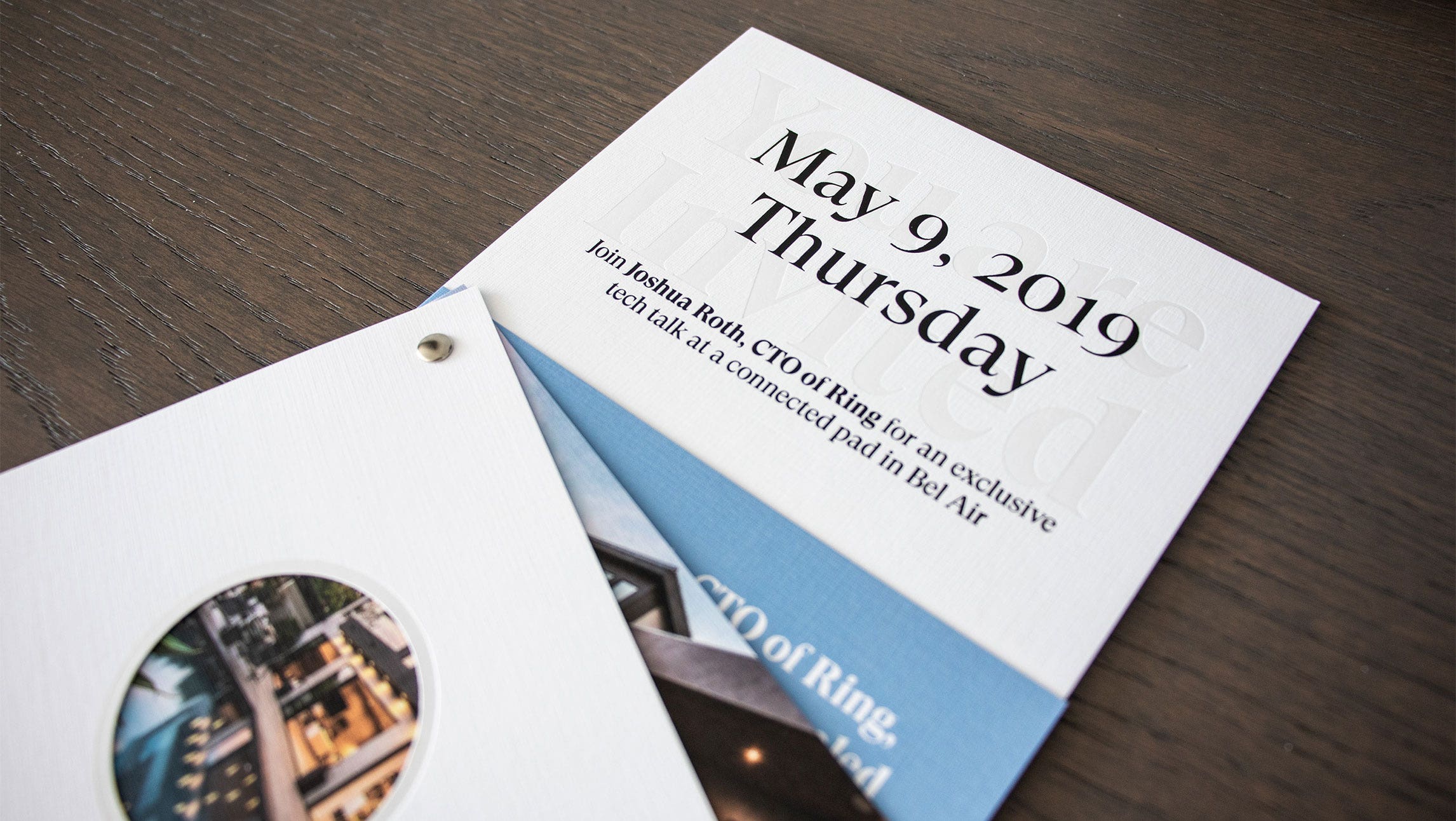 A close up photograph of the assembled Datadog x Ring invitation fanned out and placed on a dark wooden surface.